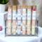 Assorted bath salts by Whole Self Aromatherapy in test tubes on elegant white linen, with a plant and pink flower in the background.
